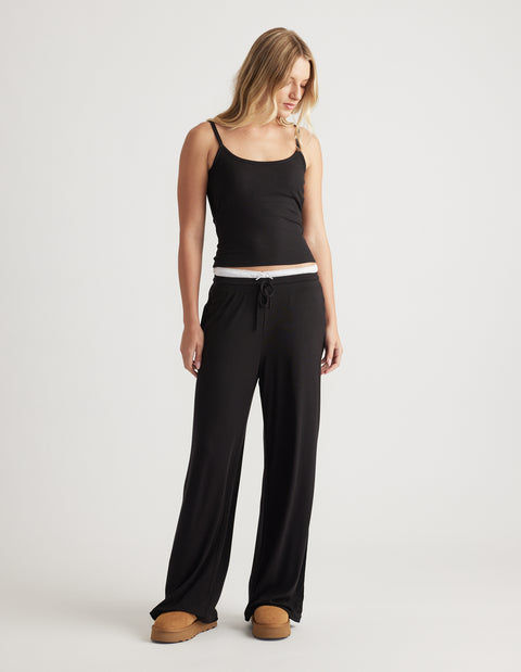 Woman wearing relaxed black ribbed wide leg pants with drawstring waist and a fitted black cami top for casual comfort