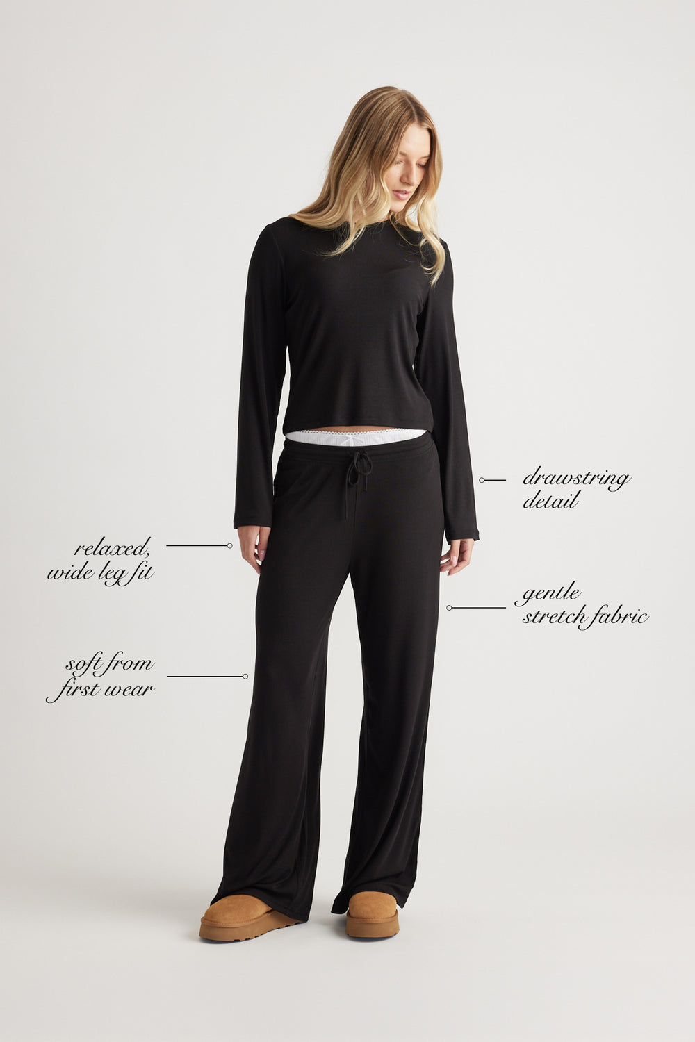 Woman dressed in black ribbed wide leg pants with drawstring waist and relaxed fit paired with a simple black long sleeve top