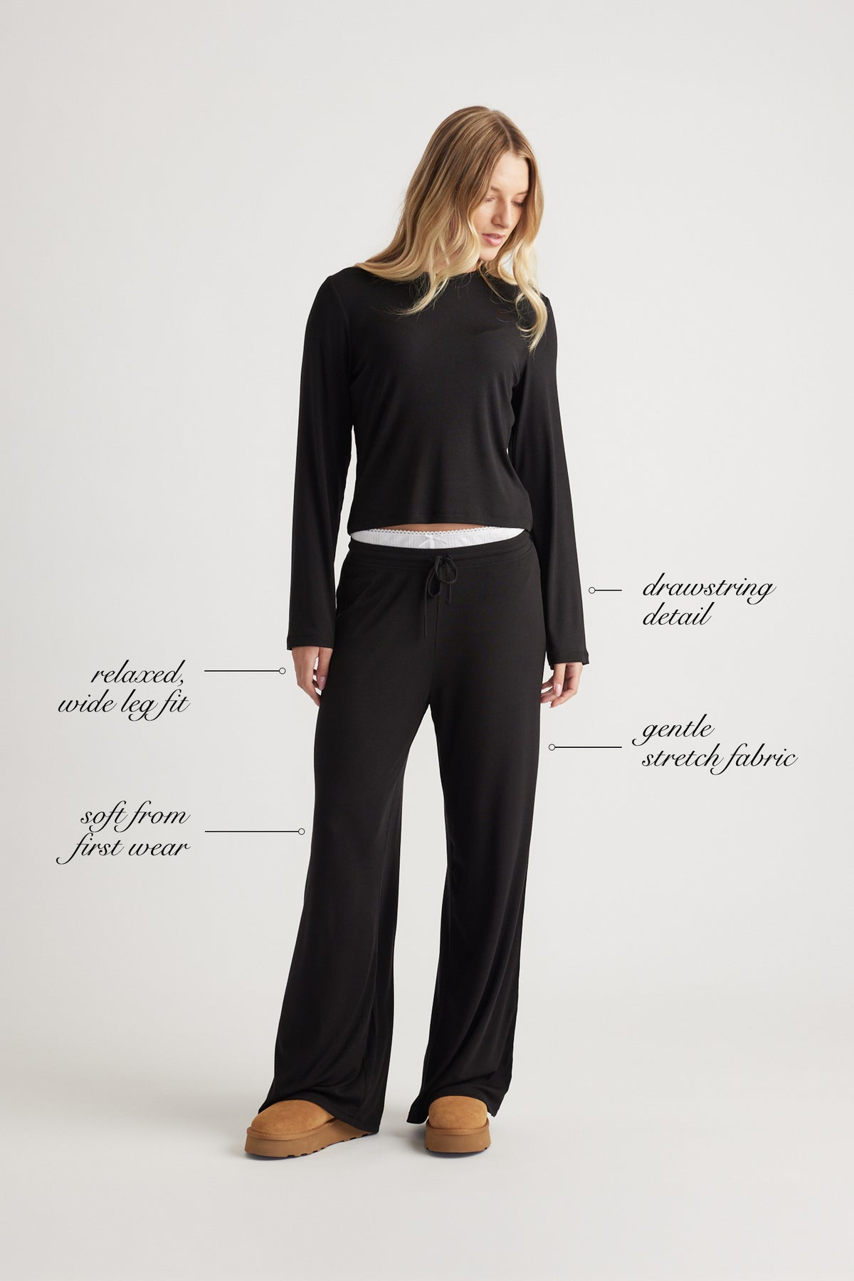 Woman dressed in black ribbed wide leg pants with drawstring waist and relaxed fit paired with a simple black long sleeve top