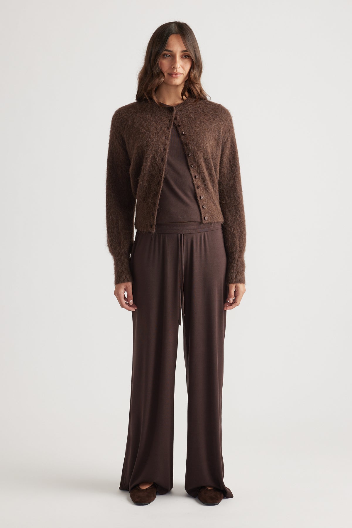 Woman wearing deep chocolate ribbed wide-leg pants paired with a fuzzy button-up cardigan and matching top