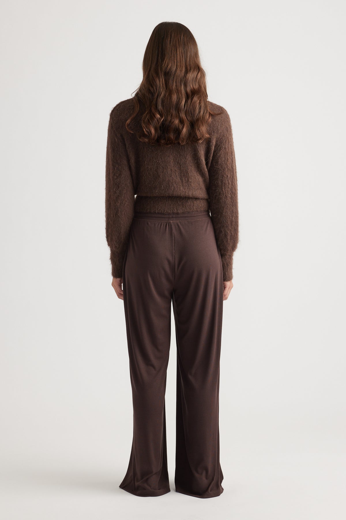 Back view of woman wearing relaxed fit ribbed wide leg pants in rich chocolate with soft textured brown sweater