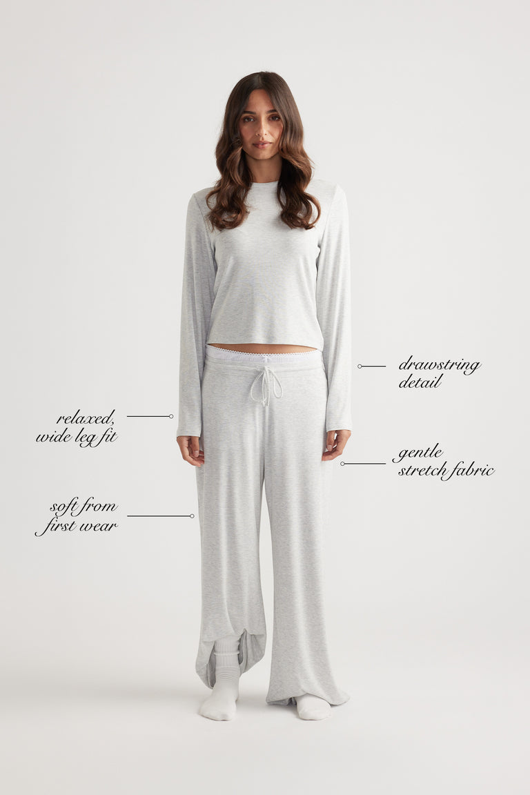 Woman wearing soft grey ribbed wide leg pants with drawstring waist and relaxed fit, paired with matching long sleeve top