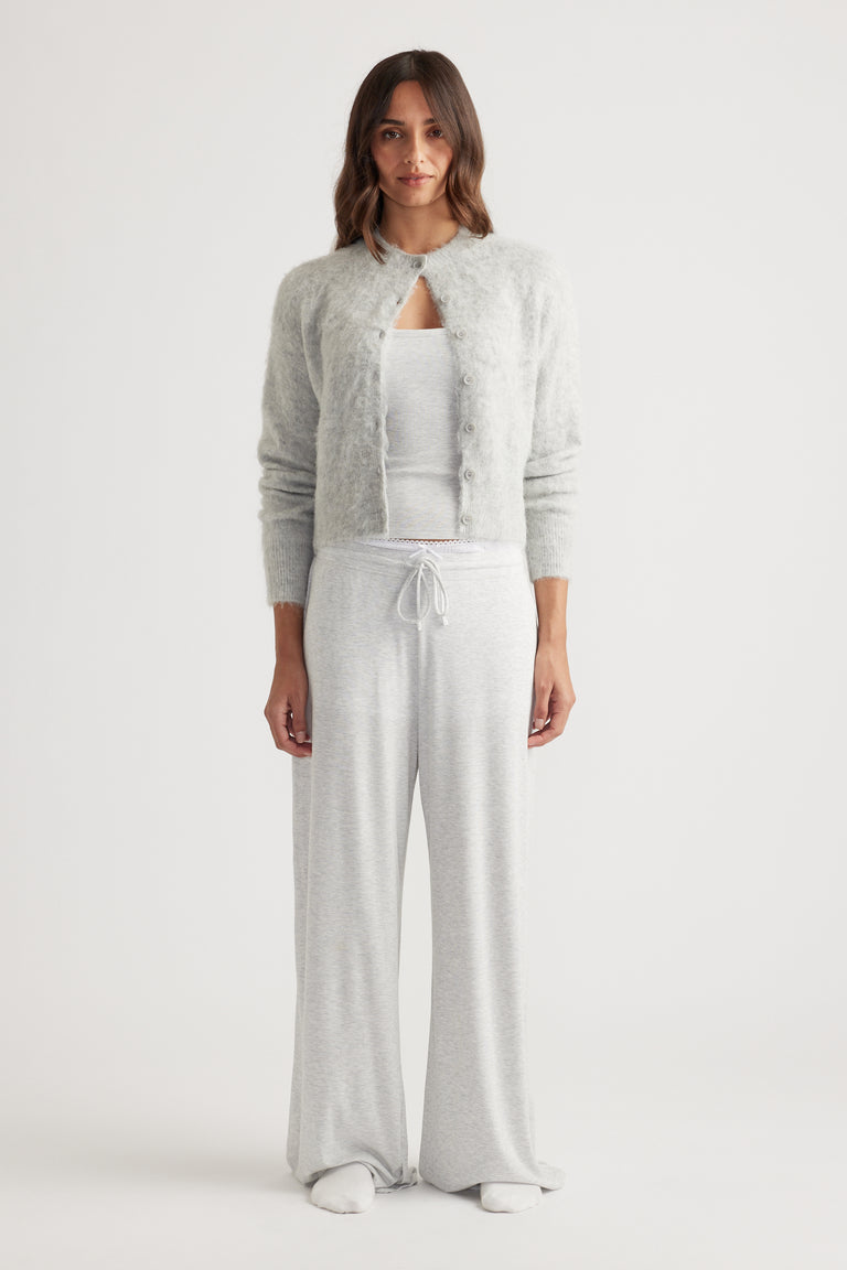 Woman wearing soft light grey wide leg pants with drawstring waist paired with a cozy button-up cardigan and tank top