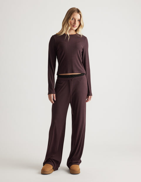 Woman wearing relaxed fit sleep ribbed wide leg pants and matching long sleeve top in soft dark brown fabric