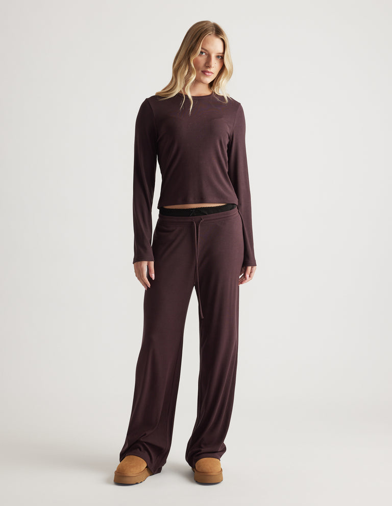 Woman wearing relaxed fit sleep ribbed wide leg pants and matching long sleeve top in soft dark brown fabric