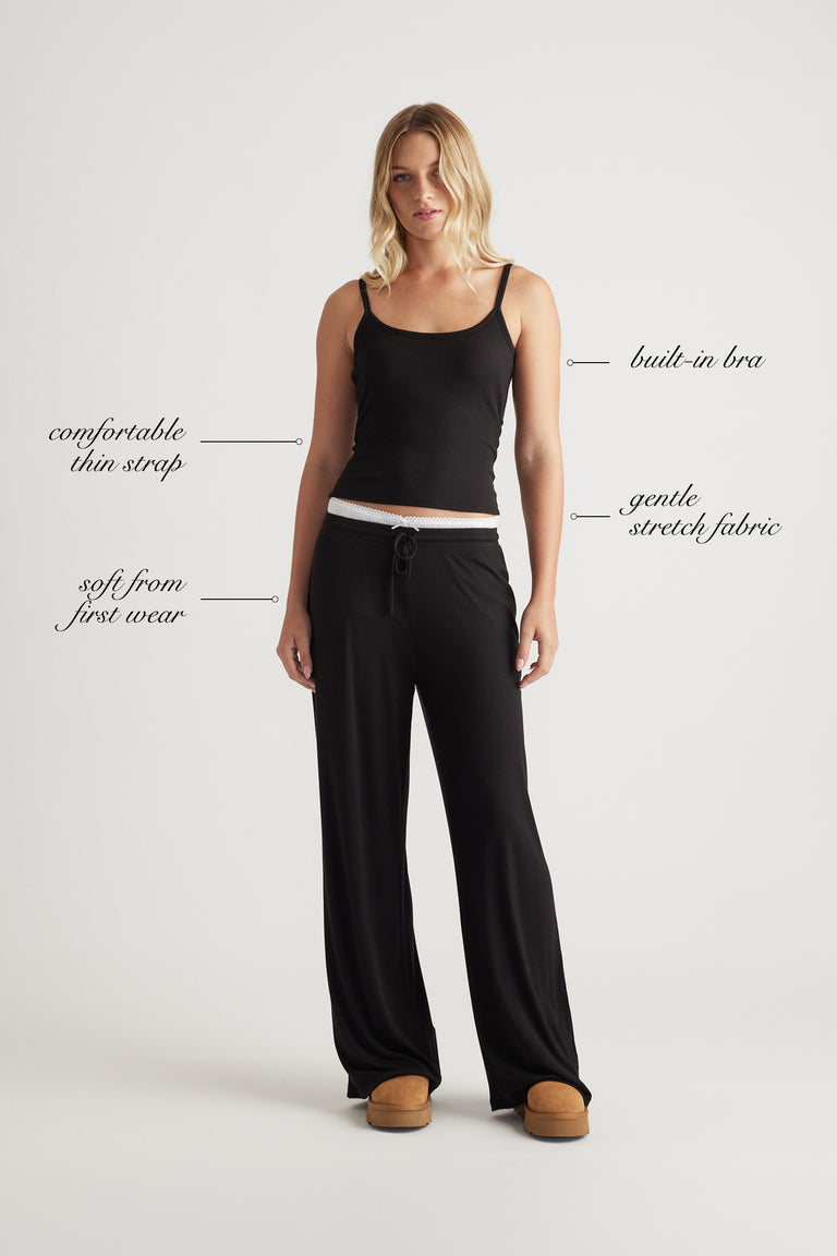 Woman wearing black ribbed cami top with built-in bra and relaxed black wide leg pants for effortless comfort