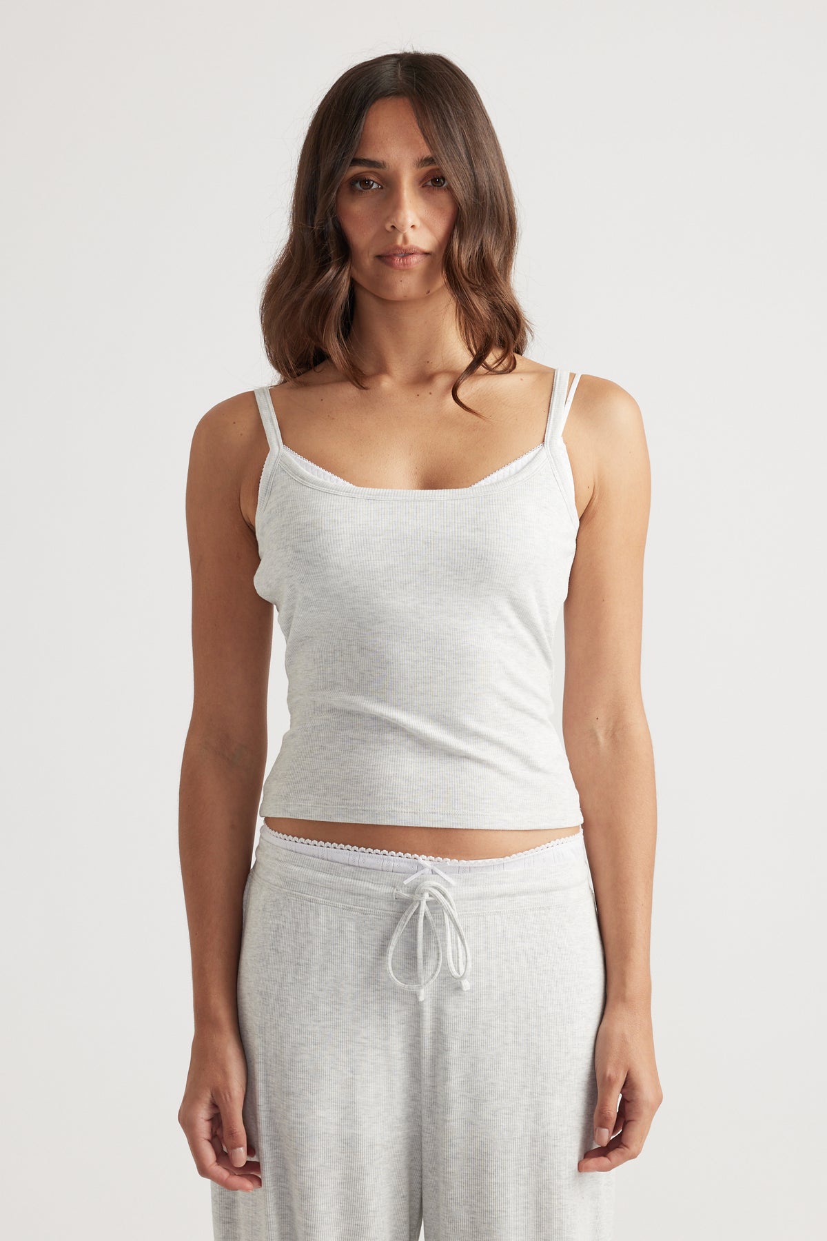 Woman wearing light grey ribbed sleep cami top paired with matching soft lounge pants for effortless comfort
