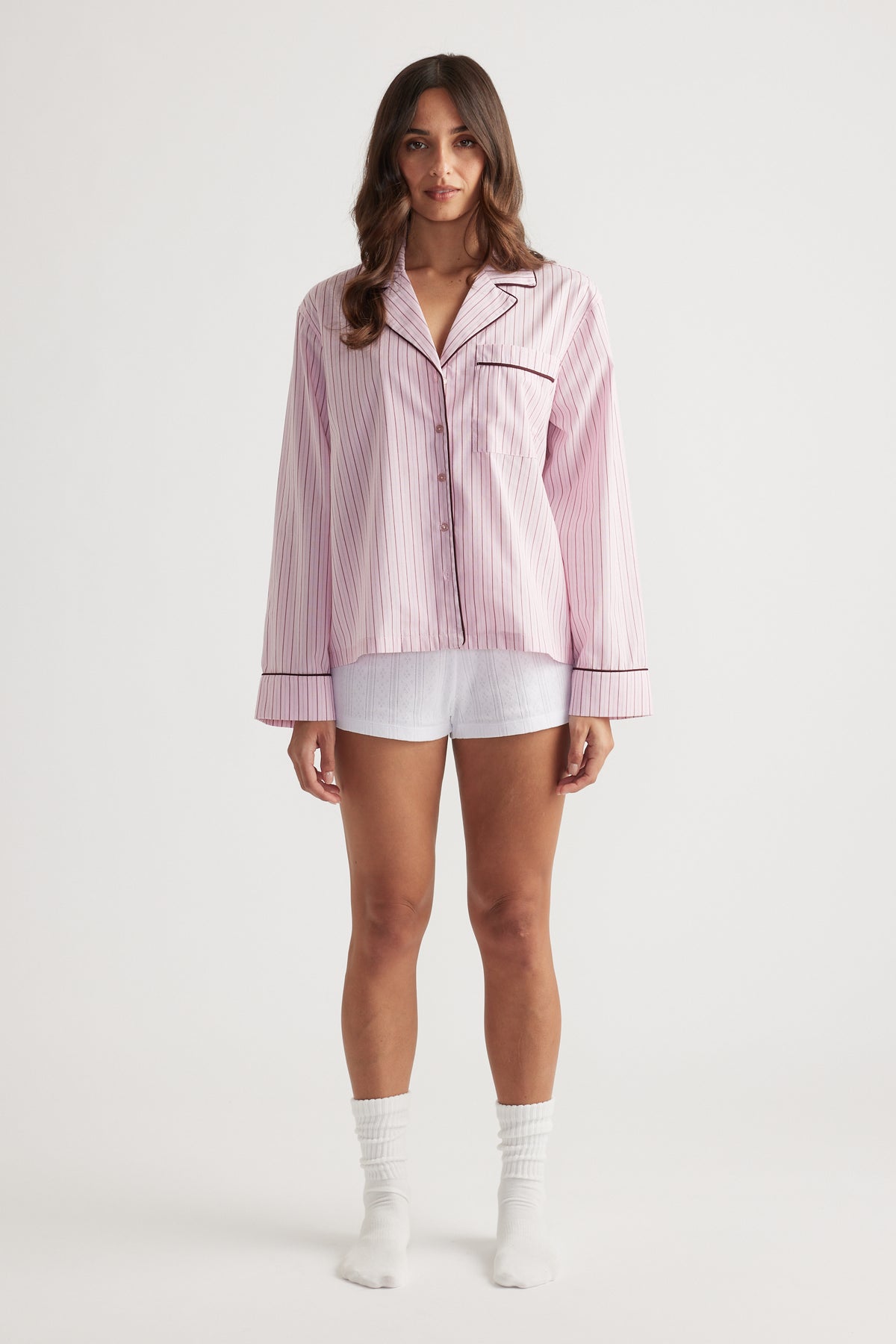 Woman wearing soft pink woven long sleeve shirt with berry stripes and contrast piping for relaxed sleepwear style