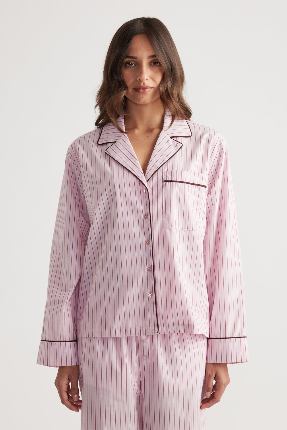 Woman wearing soft pink sleep shirt with berry vertical stripes and contrasting piping for a relaxed fit and cozy style