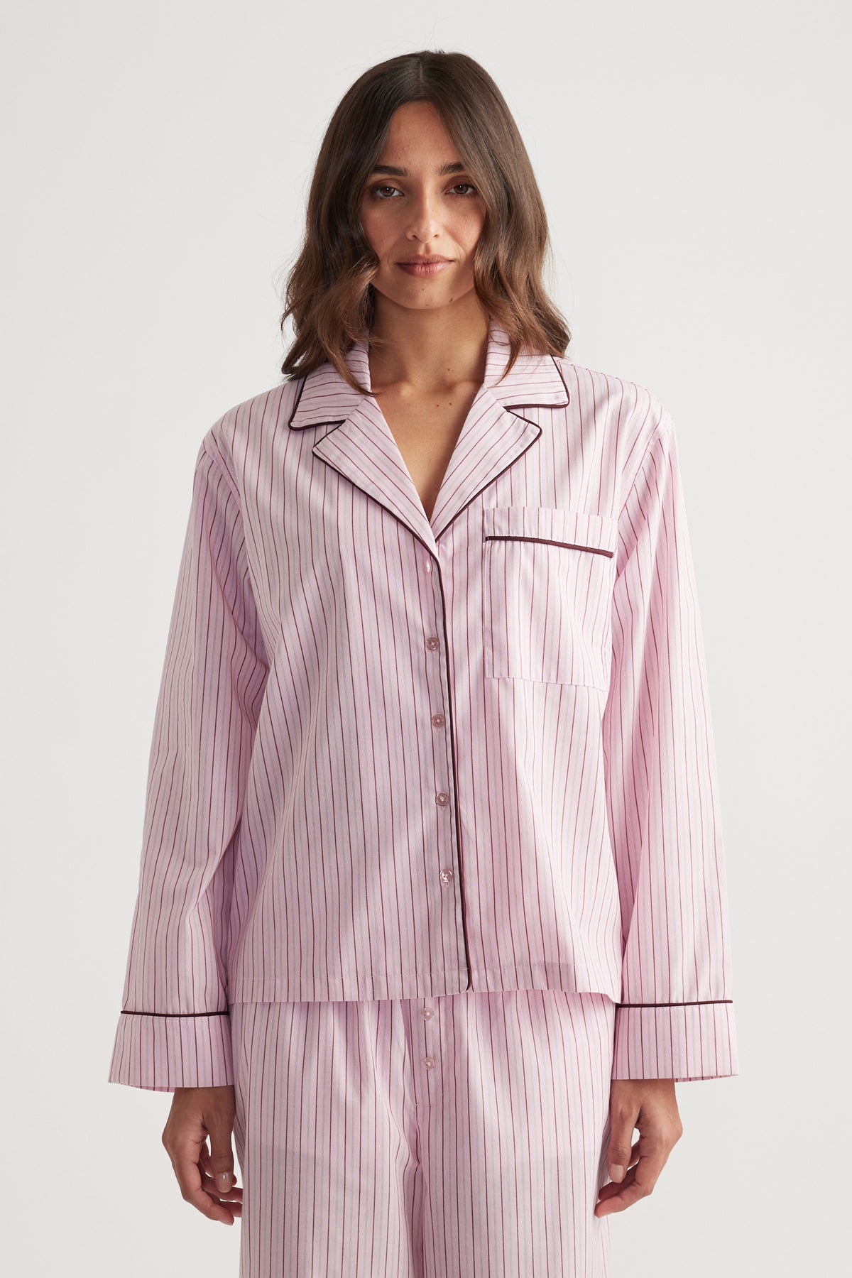 Woman wearing soft pink sleep shirt with berry vertical stripes and contrasting piping for a relaxed fit and cozy style