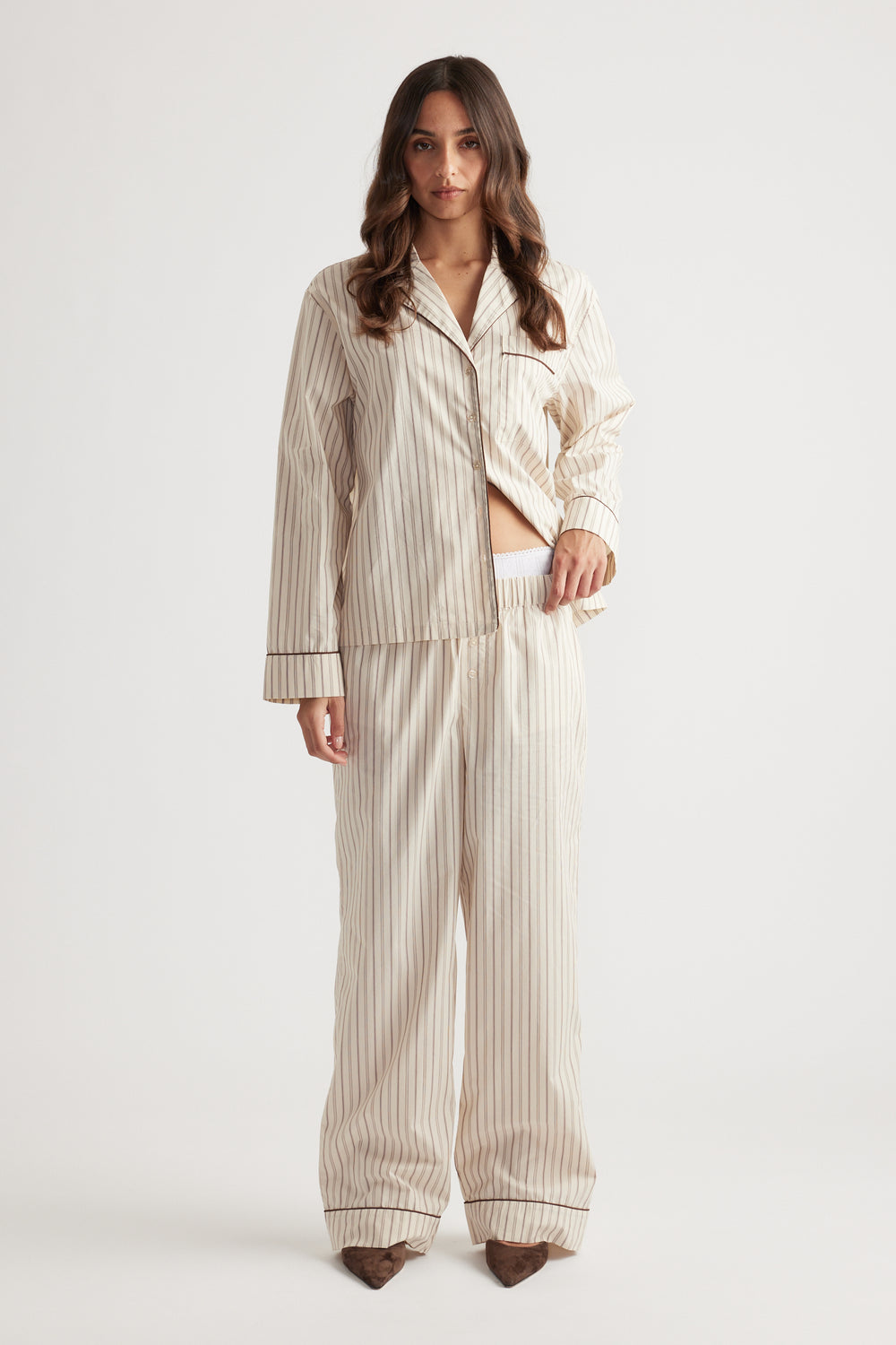 Woman wearing cream striped woven long sleeve shirt and matching wide-leg pants standing against white background