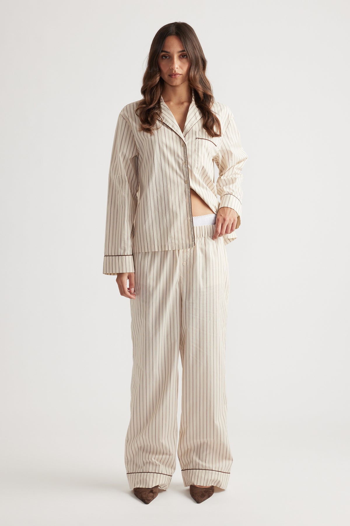 Woman wearing cream striped woven long sleeve shirt and matching wide-leg pants standing against white background