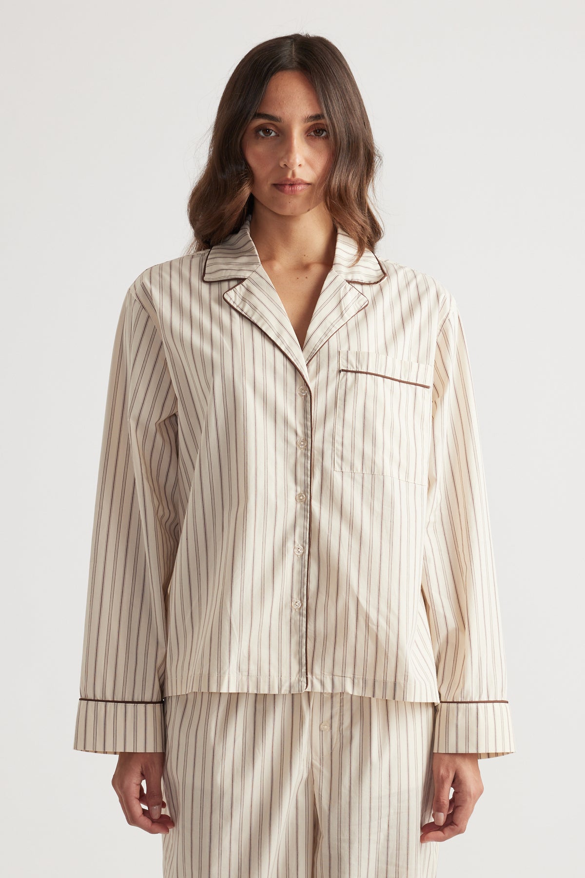 Woman wearing cream and brown striped sleep woven long sleeve shirt with matching relaxed pants in soft fabric