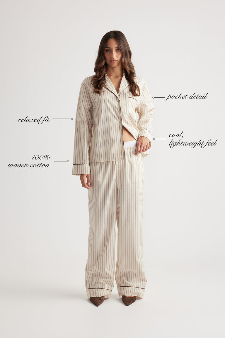 Woman wearing cream striped sleep shirt and matching wide-leg woven cotton pants with relaxed fit and pocket detail