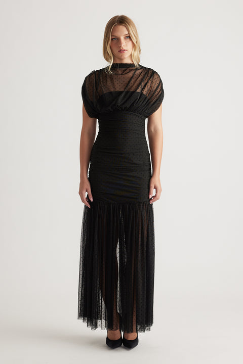 Front view of a woman wearing a black high neck mesh maxi dress with puffed sleeves and a sheer textured skirt panel