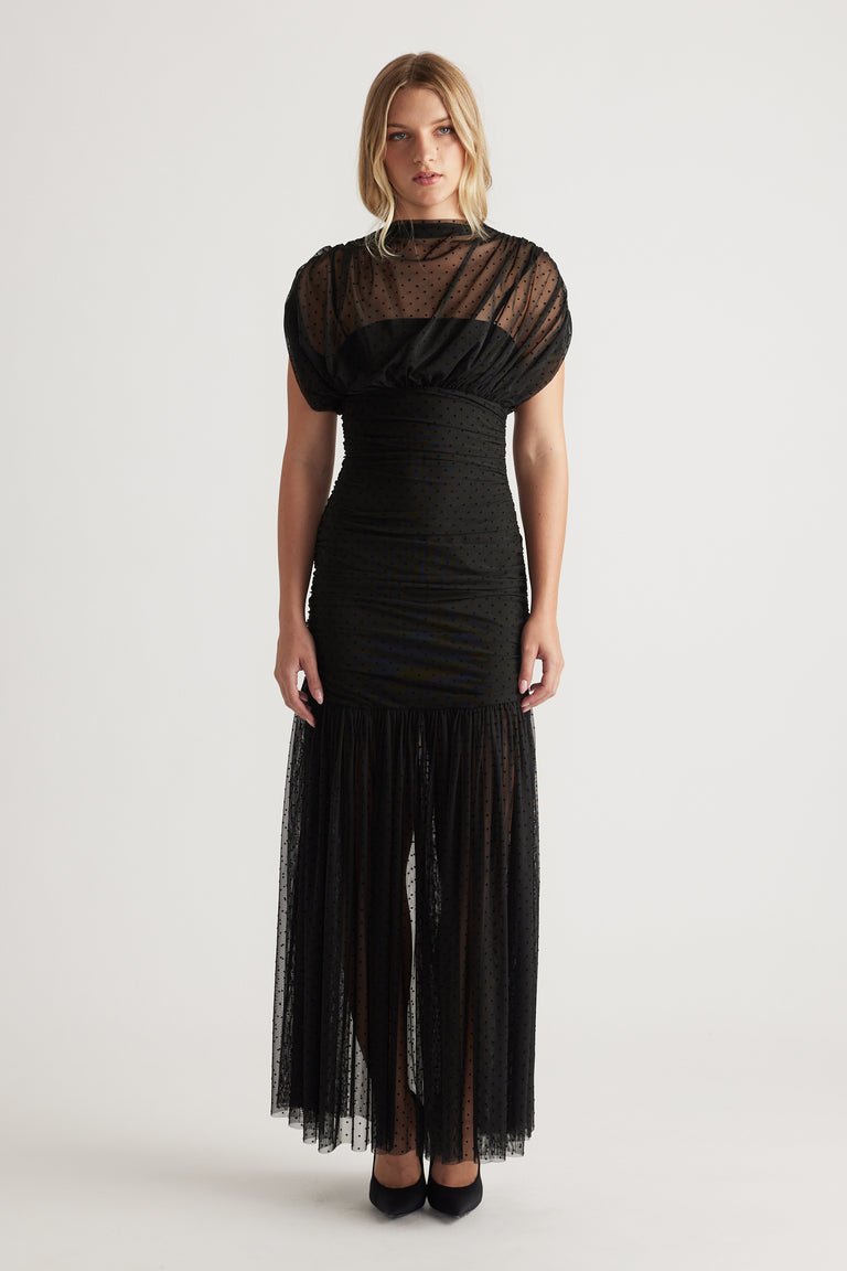 Front view of a woman wearing a black high neck mesh maxi dress with puffed sleeves and a sheer textured skirt panel