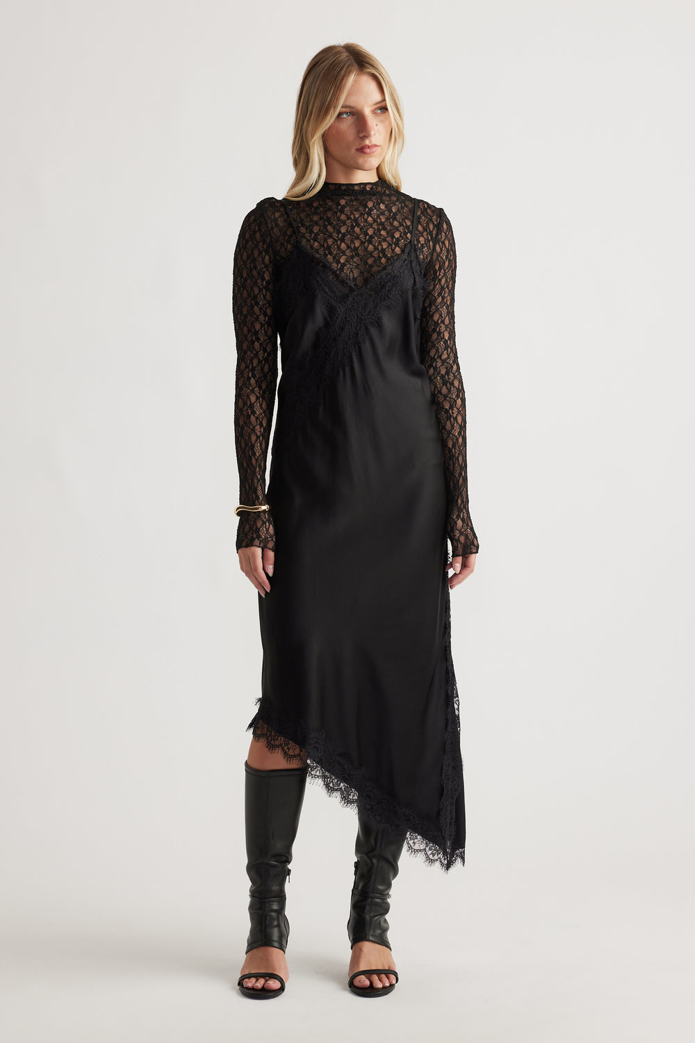 Woman wearing sleek black slip dress with lace trim over patterned mesh long-sleeve top, styled with Ella Wavy Bracelet