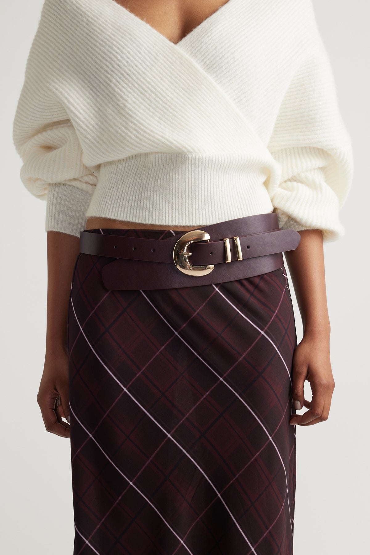 Vicci Wrap Belt in rich burgundy leather with a bold gold buckle, styled over a patterned skirt for a chic look.