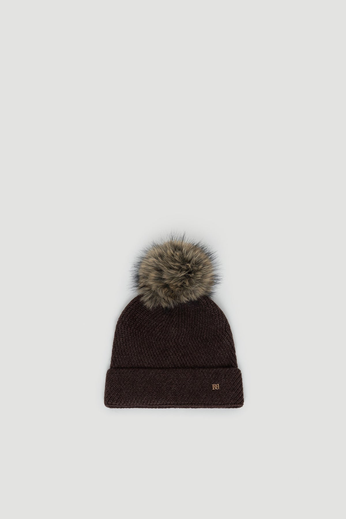 Dark chocolate knit beanie with a fluffy faux fur pom pom and subtle gold-tone logo detail on cuff.
