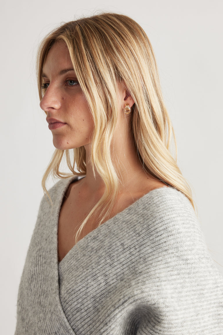 Close-up of woman wearing gold-tone Eden Earring Multi Pack styled with soft grey knitwear for a subtle, elegant look.