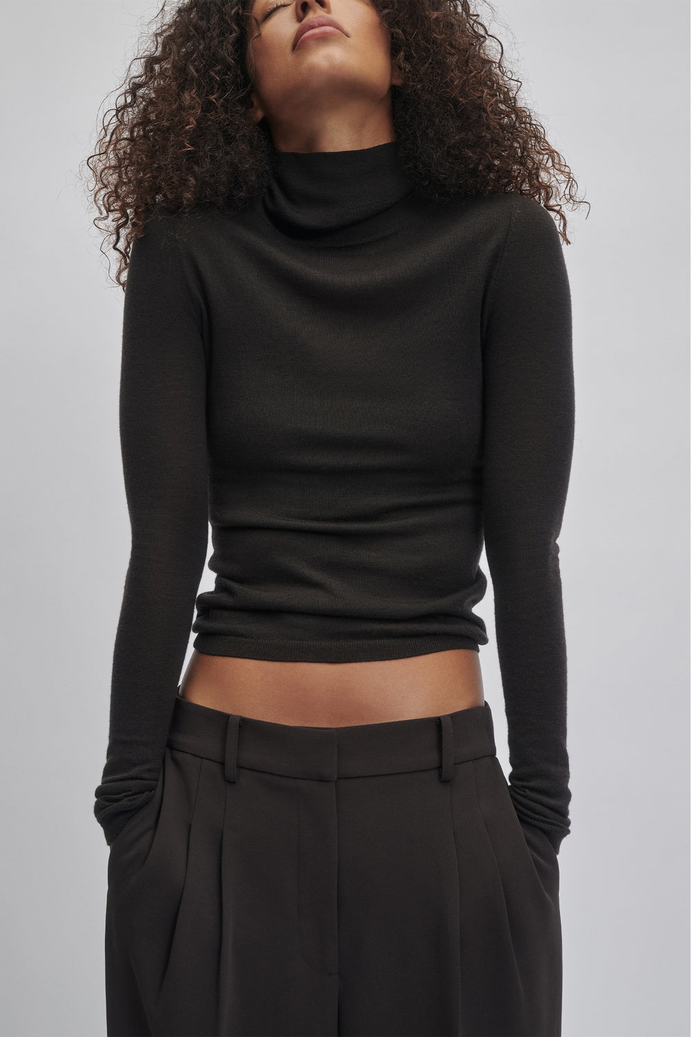 Slim fit black fine wool knit top with long sleeves and a relaxed turtleneck for effortless everyday style.