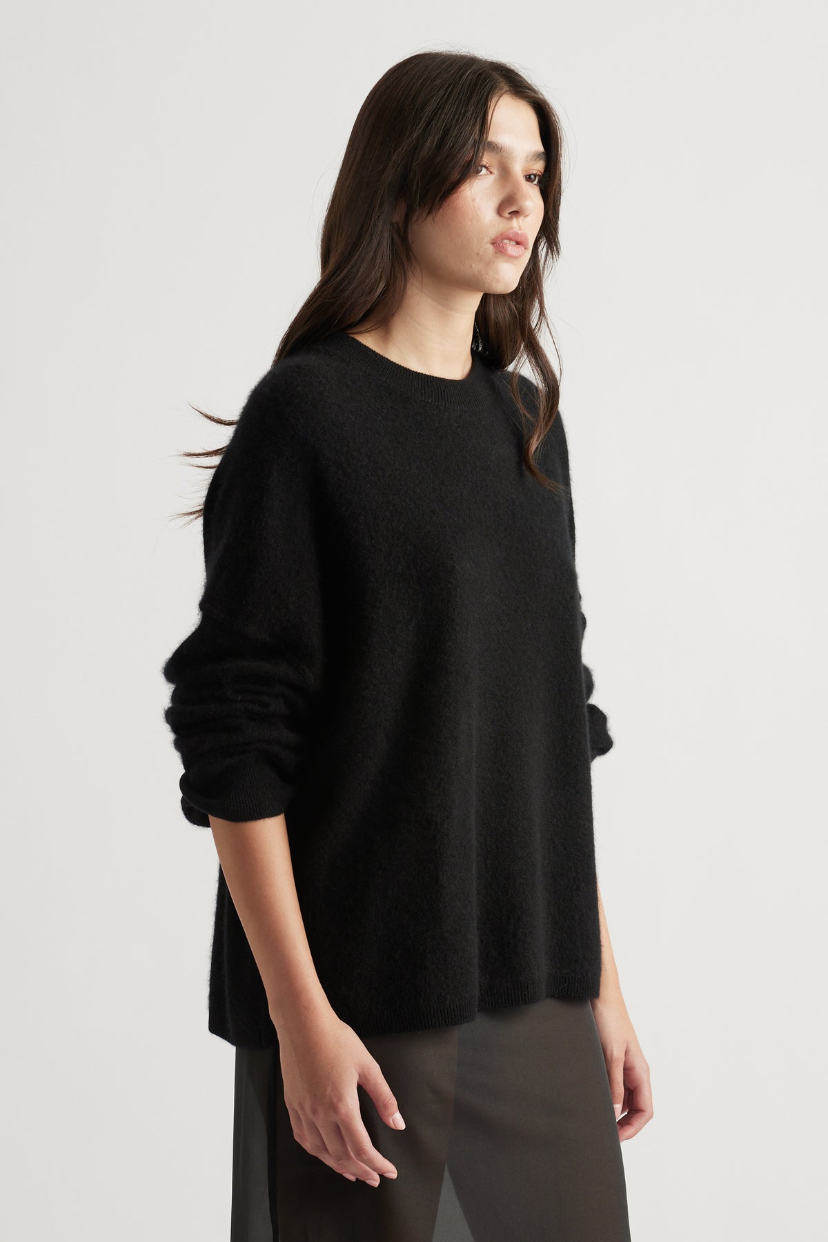 Woman wearing a cozy oversized black wool knit with long sleeves and relaxed fit, styled in a minimalistic look