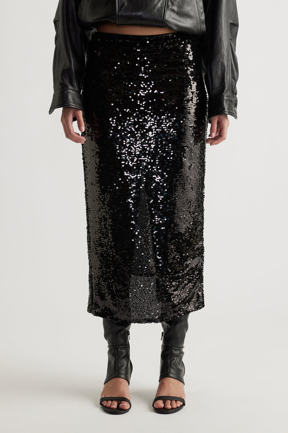 Black sequin midi skirt styled with open-toe heels and a cropped black leather jacket for a sleek look