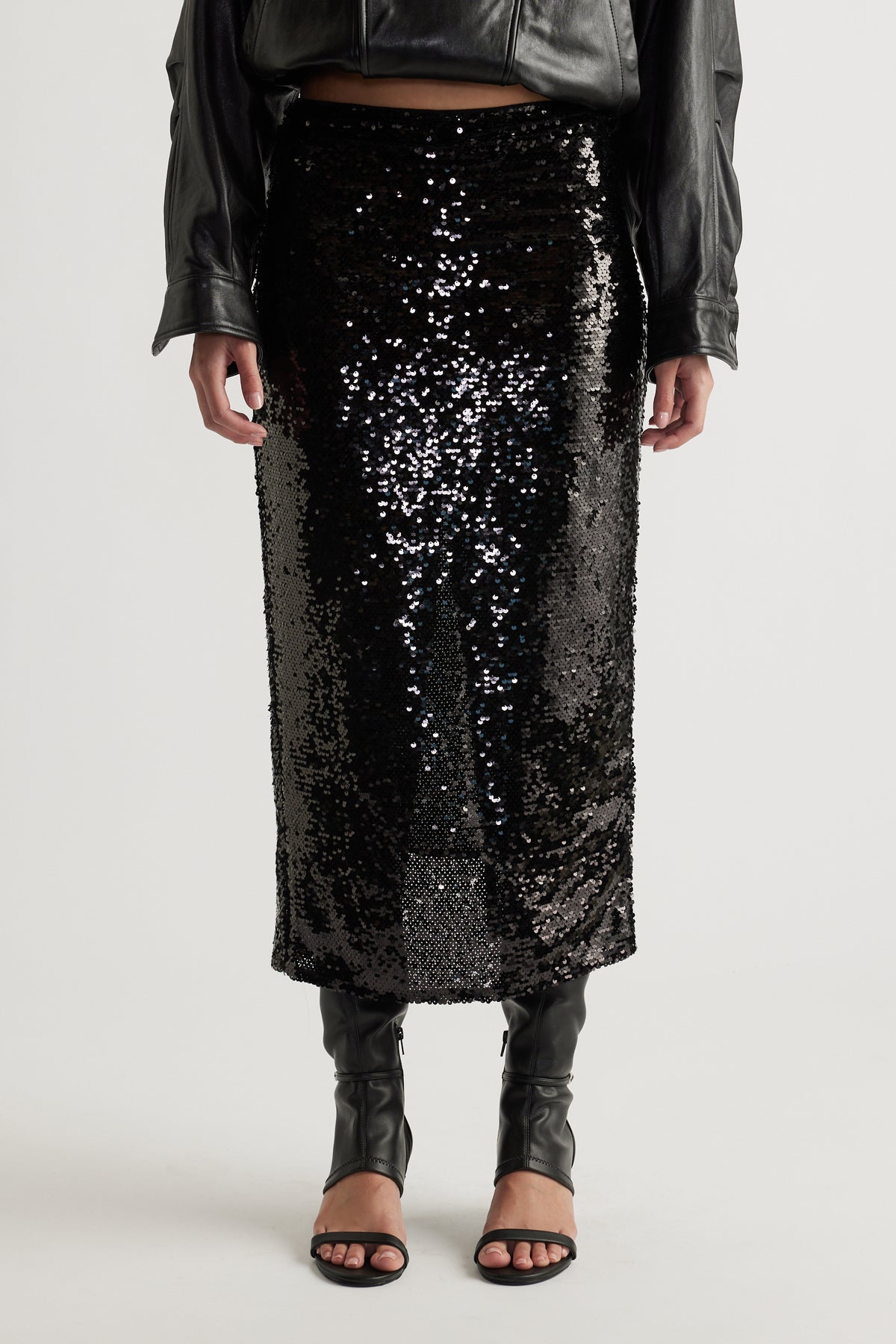 Black sequin midi skirt styled with open-toe heels and a cropped black leather jacket for a sleek look
