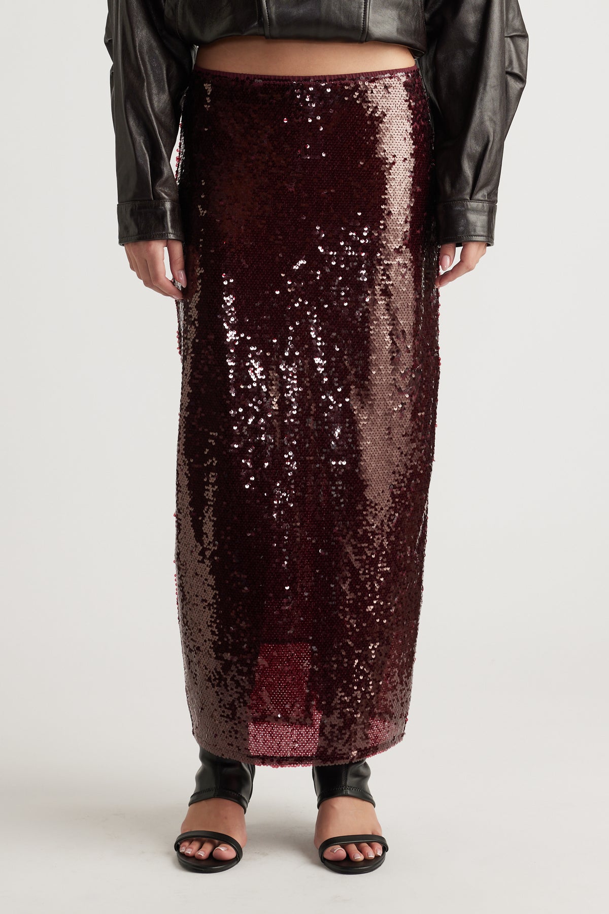 Rich plum sequin maxi skirt with a straight silhouette, styled with black open-toe heels and a cropped jacket.