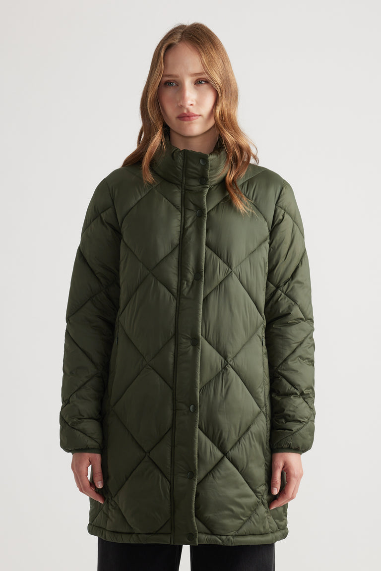 Woman wearing a moss green quilted longline puffer jacket with a high collar for a cozy layered look