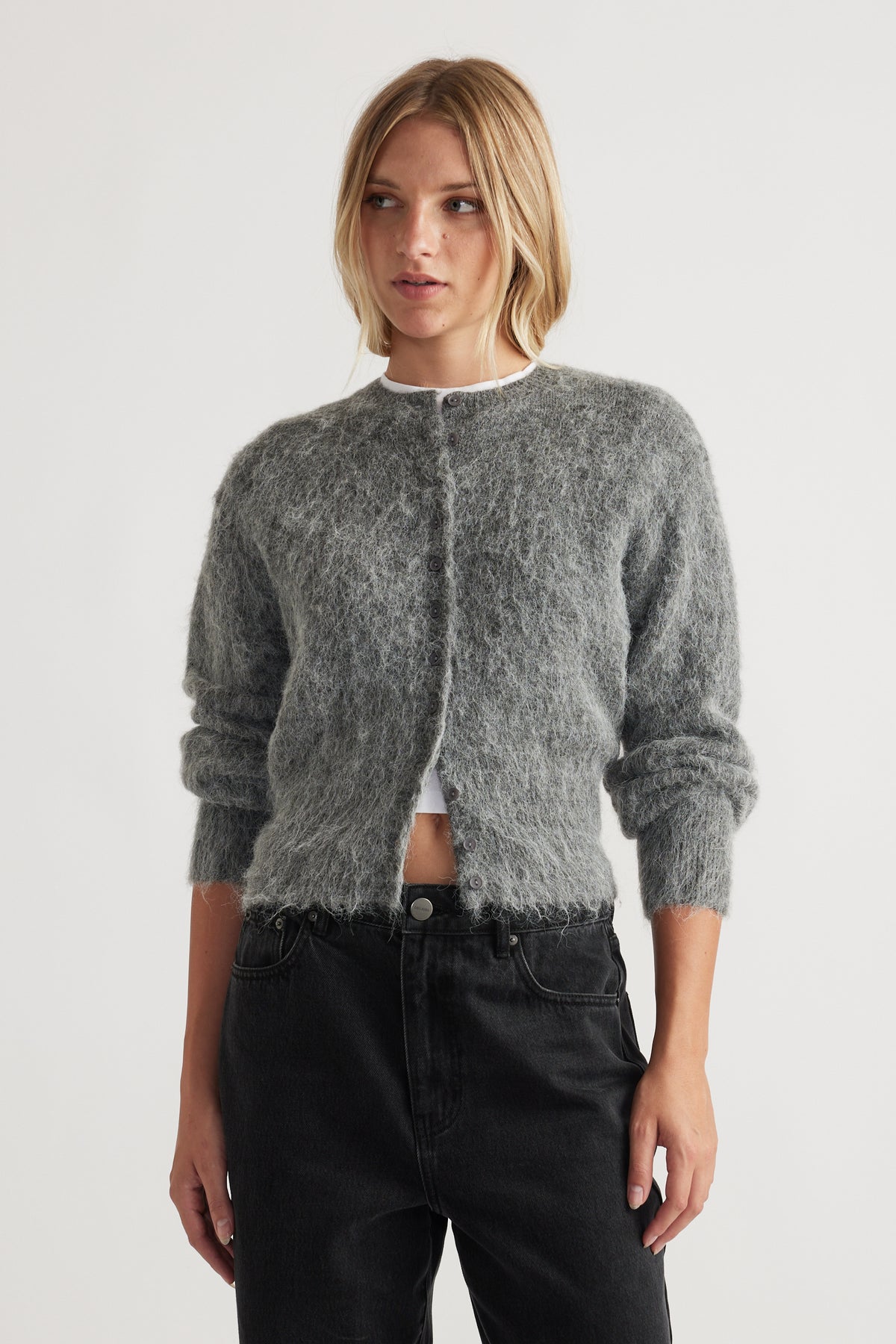 Woman wearing a soft charcoal grey button-up cardigan with long sleeves and relaxed black high-rise jeans