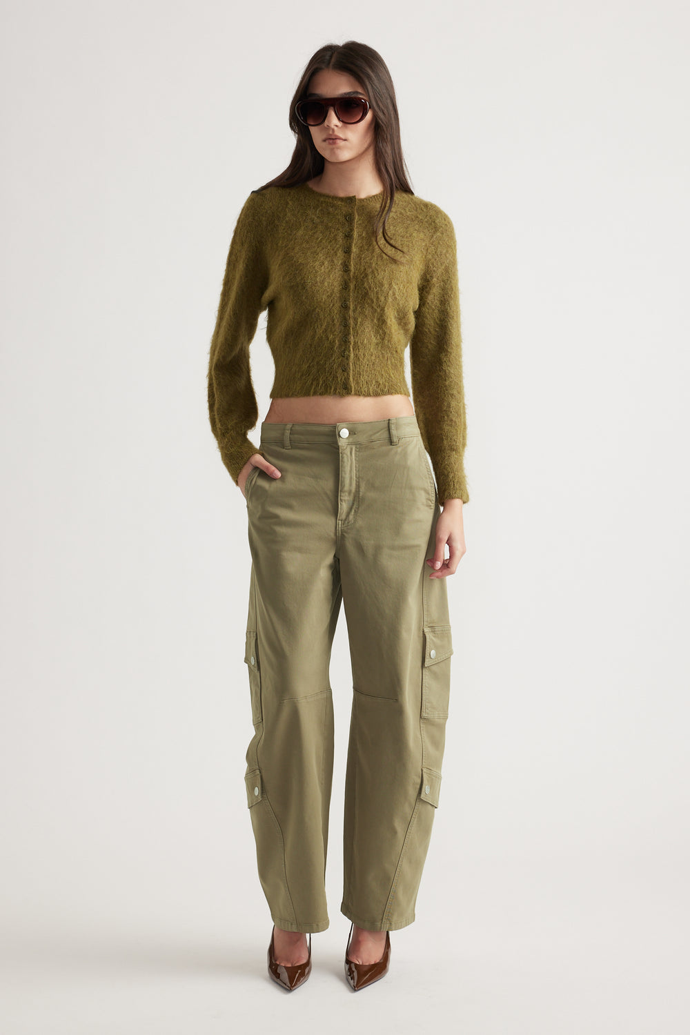 Woman wearing a cropped olive button-up cardigan paired with high-waisted cargo pants and brown pointed heels