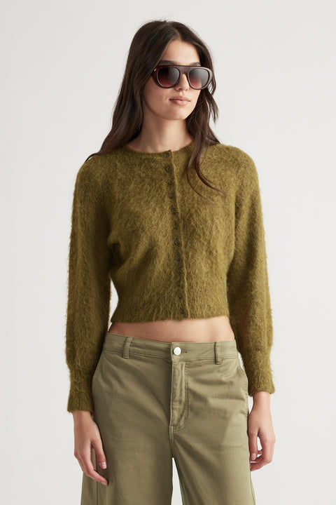 Woman wearing a textured olive green button-up cardigan with long sleeves and relaxed fit high-waisted pants