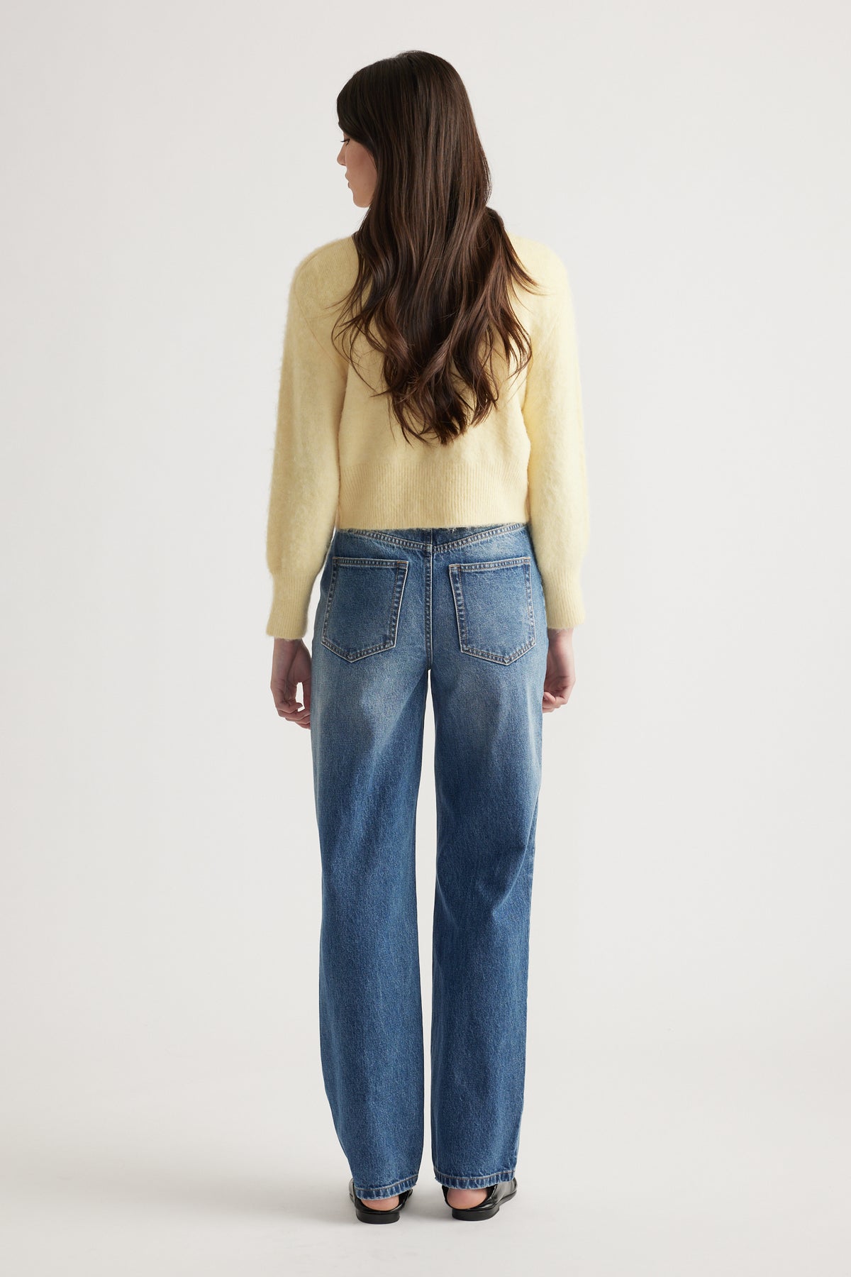 Woman wearing a soft yellow cardigan paired with relaxed fit classic blue jeans, styled for effortless everyday wear