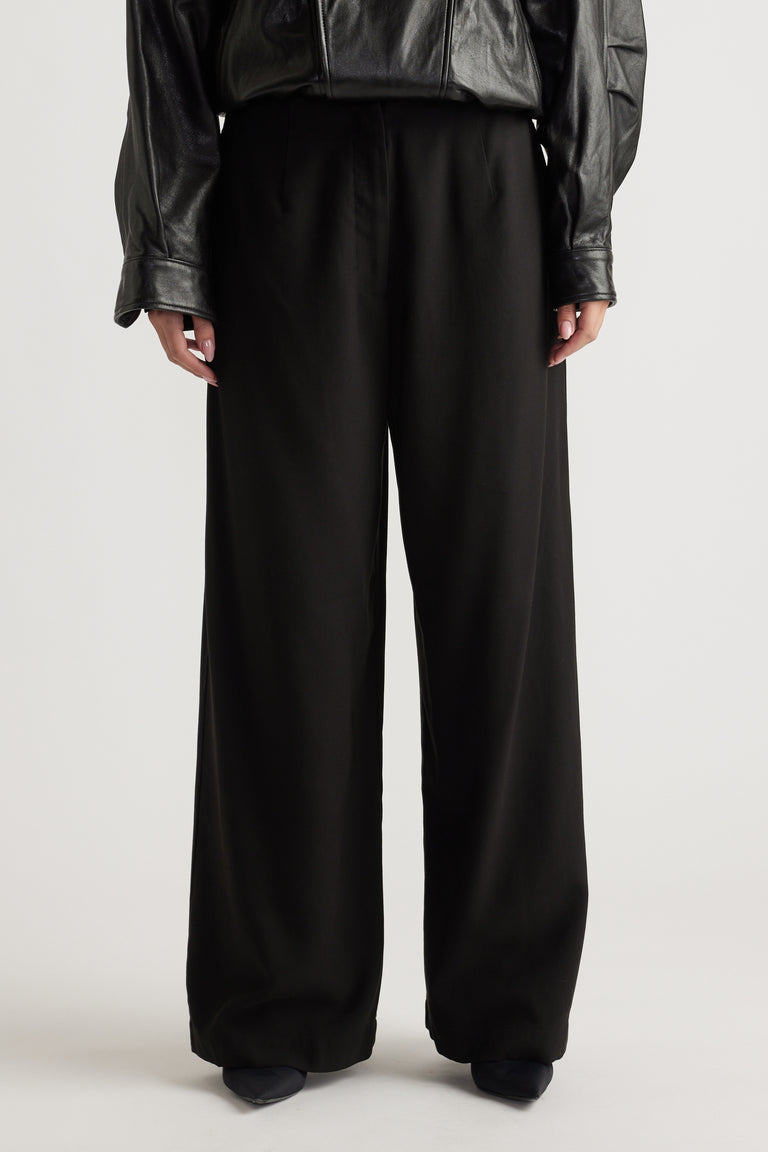 Front view of relaxed black wide-leg pants paired with a black faux leather top for a chic, effortless look.