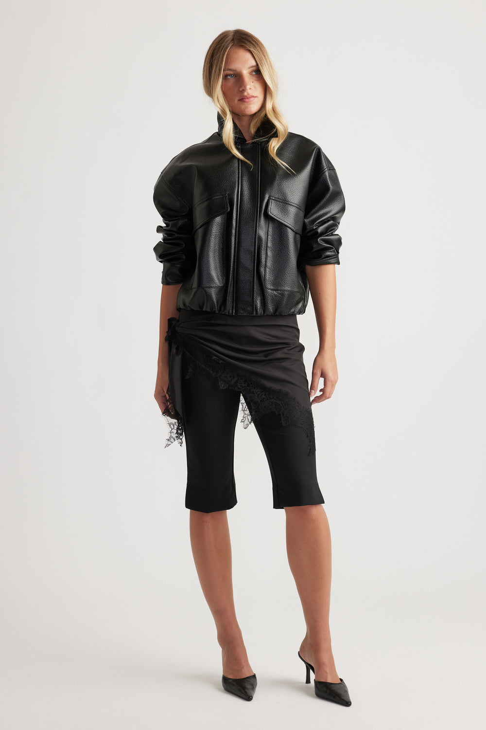 Model wearing Melanie Capri Pant in black with lace trim detail, paired with a textured black jacket by Decjuba Australian brand