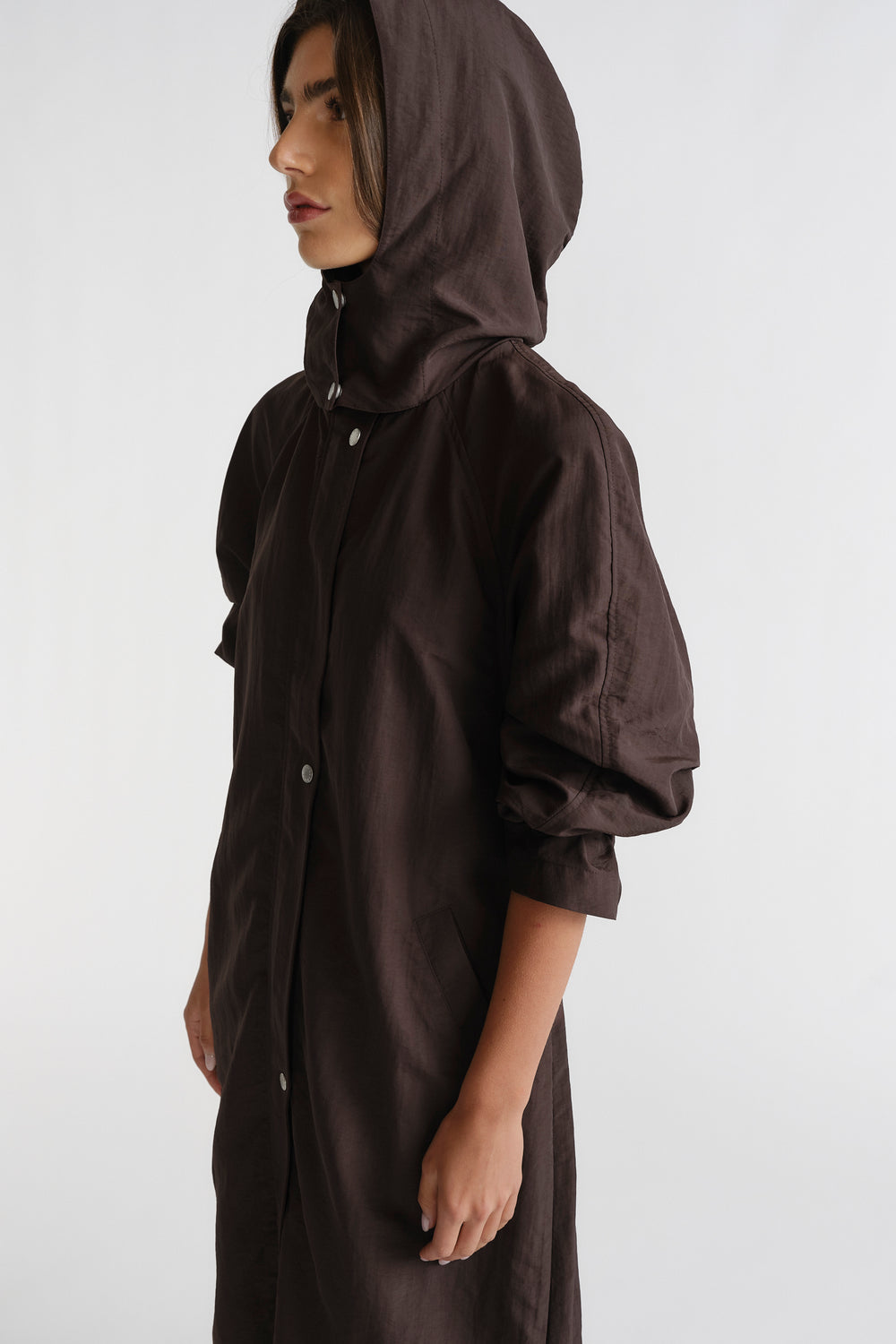 Woman in profile wearing a cocoa brown D-Luxe Anorak with a hood and relaxed sleeves, showcasing effortless style.