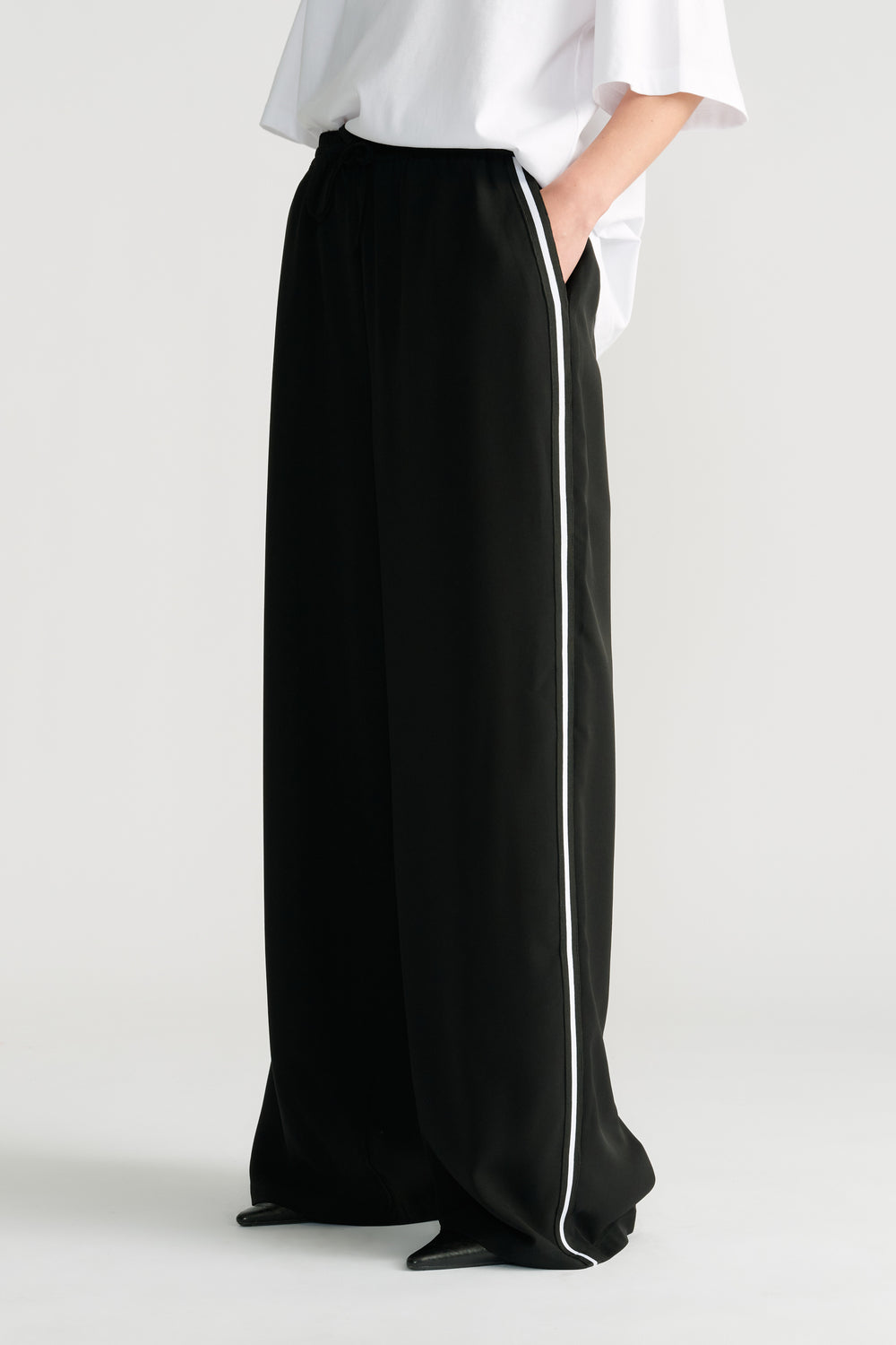 Black wide-leg pants with a relaxed fit featuring a contrasting side stripe and an elastic waistband.