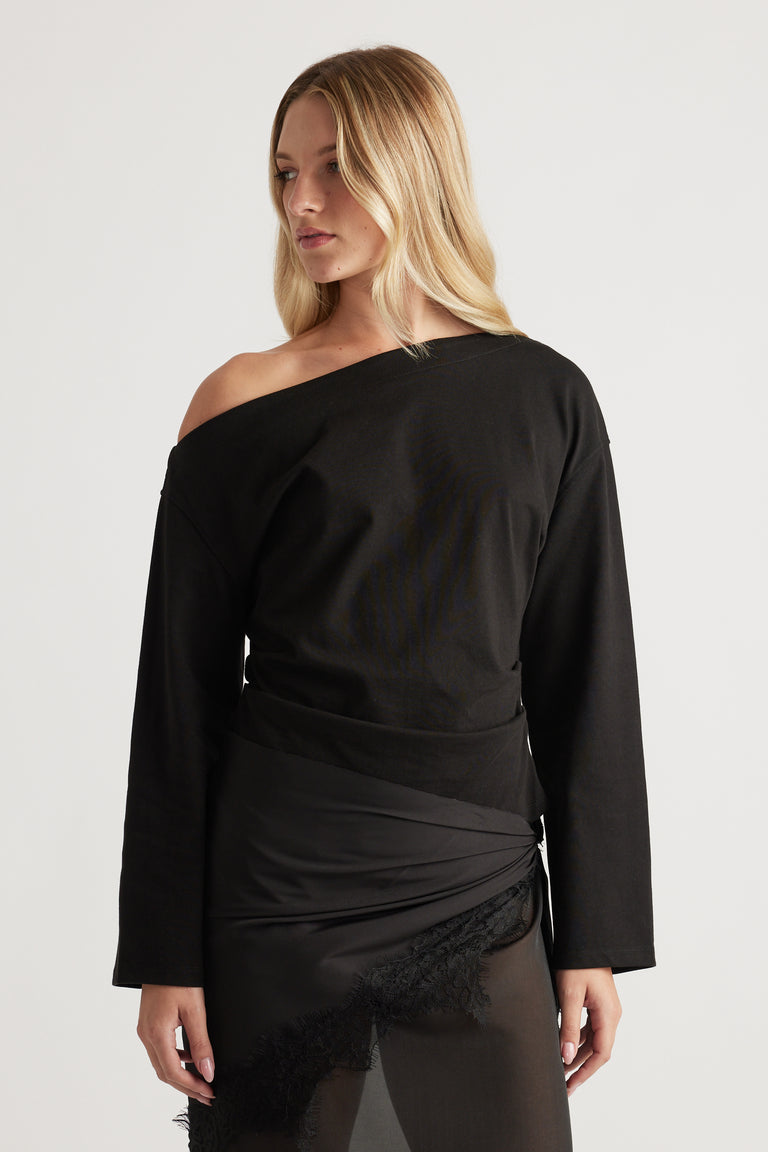 Woman wearing a black off-shoulder long sleeve top paired with a sheer lace-trimmed skirt for an elegant look