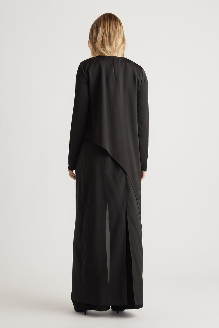 Back view of a woman wearing a black satin drape top paired with wide-leg black pants for a sleek look