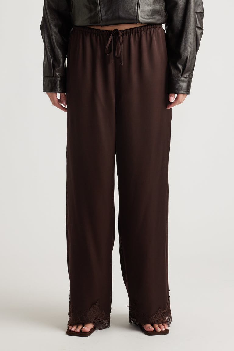 Dark brown satin pants with relaxed fit and delicate lace trim at the wide hems for a chic, comfortable look.