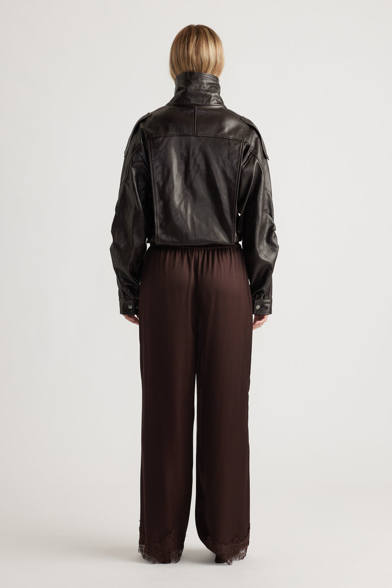 Back view of rich brown satin pants with lace trim at the hem, styled with a cropped black leather jacket