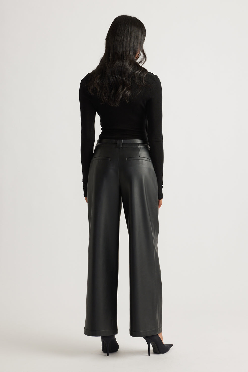 Back view of black wide-leg faux leather pants paired with a fitted long sleeve top and heels for a sleek look