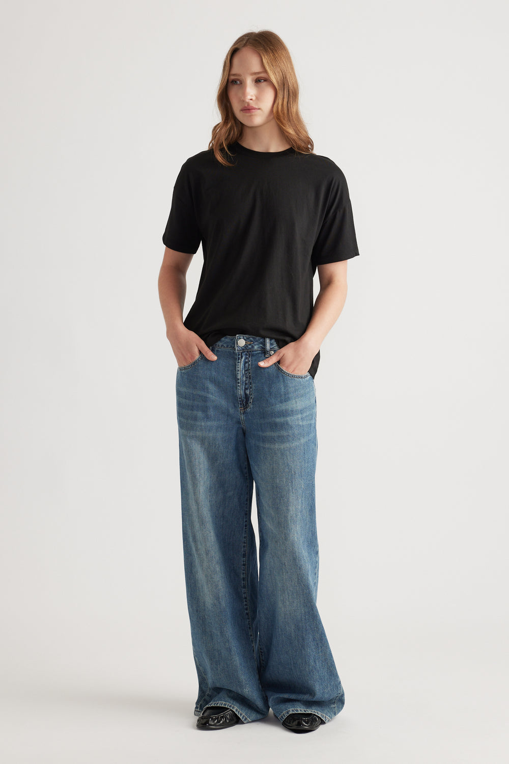 Woman wearing a relaxed black short sleeve tee paired with wide-leg blue denim jeans for an easy casual outfit