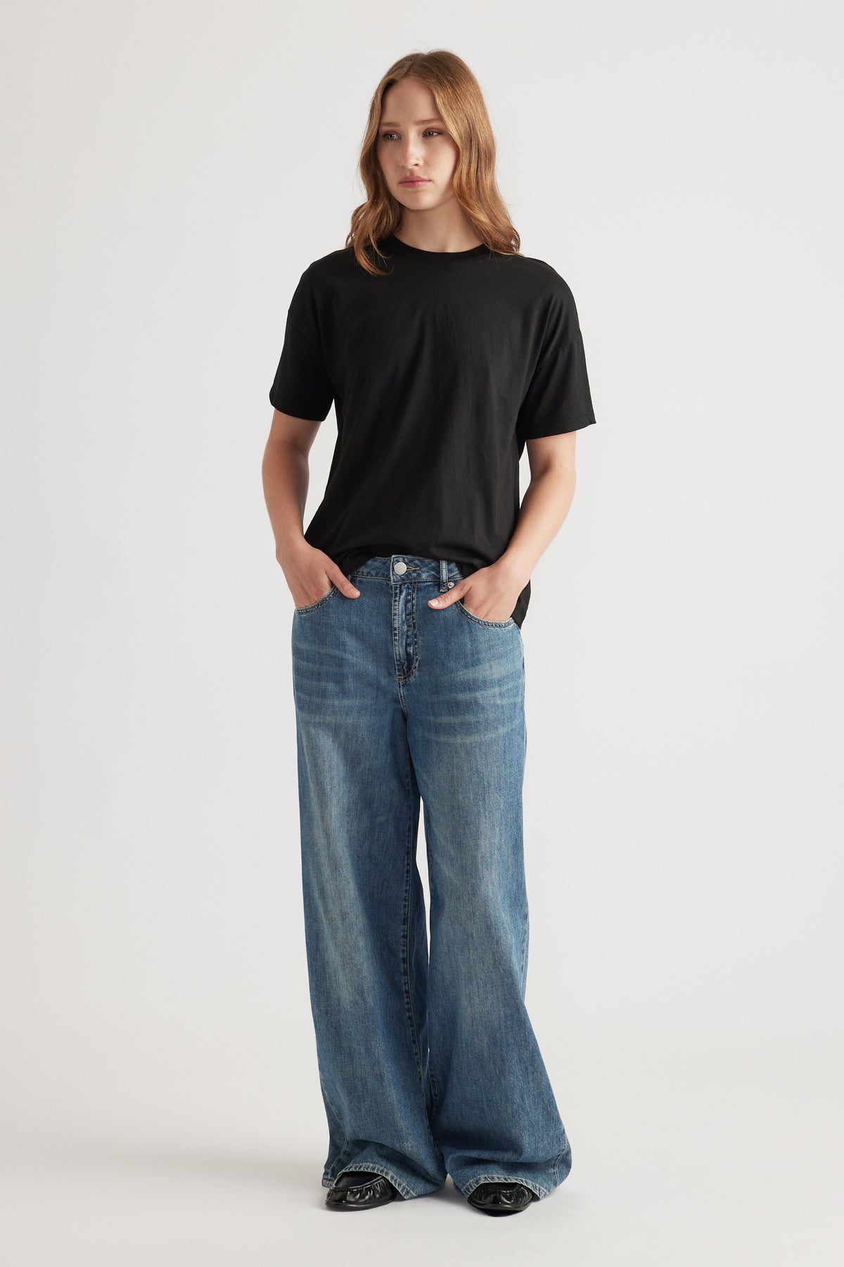 Woman wearing a relaxed black short sleeve tee paired with wide-leg blue denim jeans for an easy casual outfit