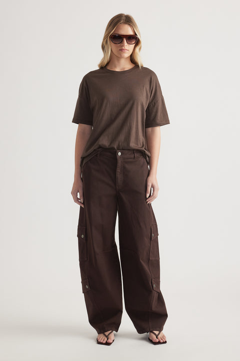 Woman wearing a relaxed brown crew neck tee with dark brown cargo pants, sunglasses and flat sandals
