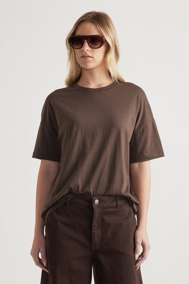 Woman wearing a relaxed brown crew neck short sleeve tee with dark brown jeans and sunglasses