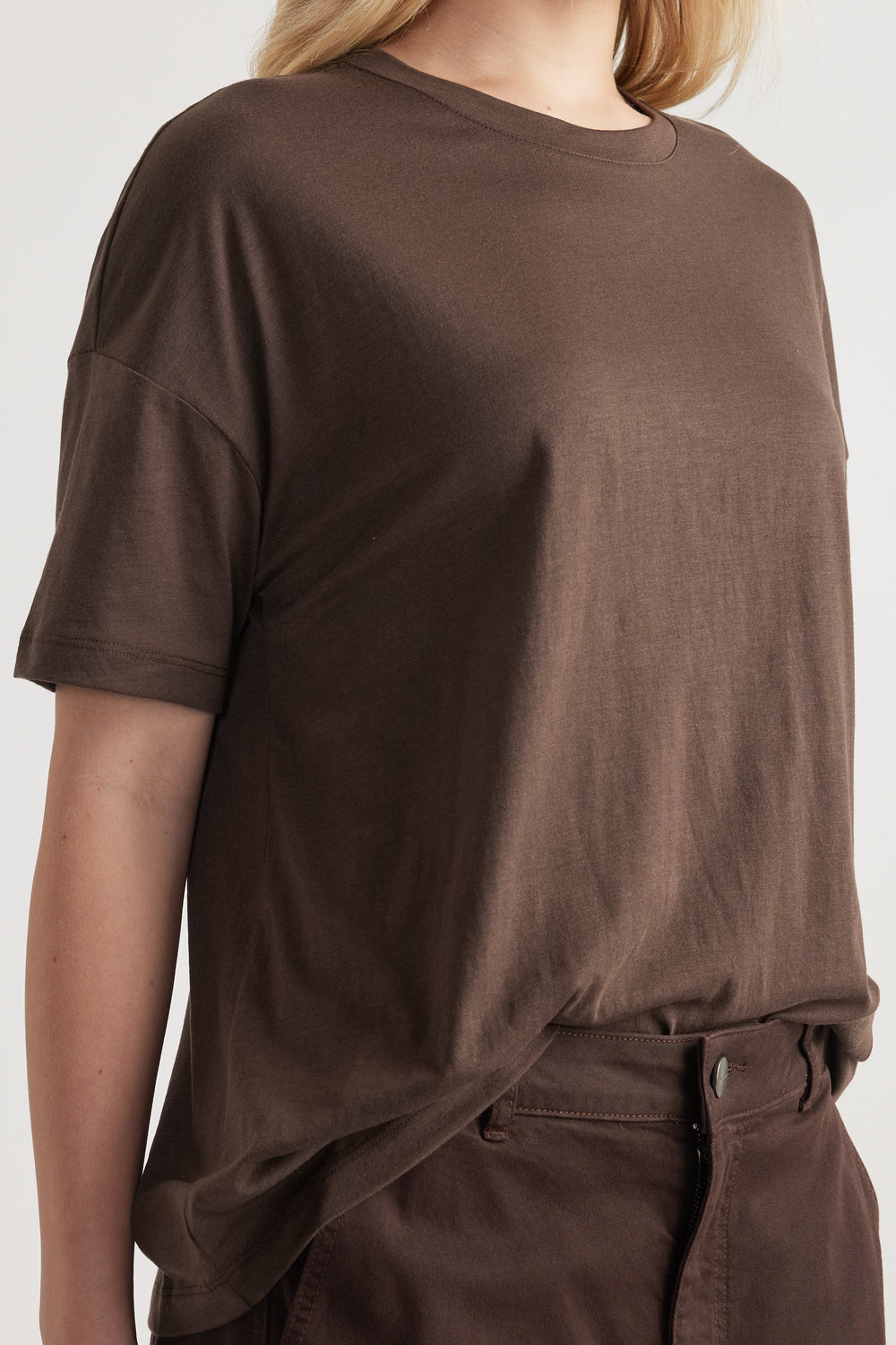 Woman wearing a relaxed dark brown short sleeve crew neck tee with drop shoulders and full length fit