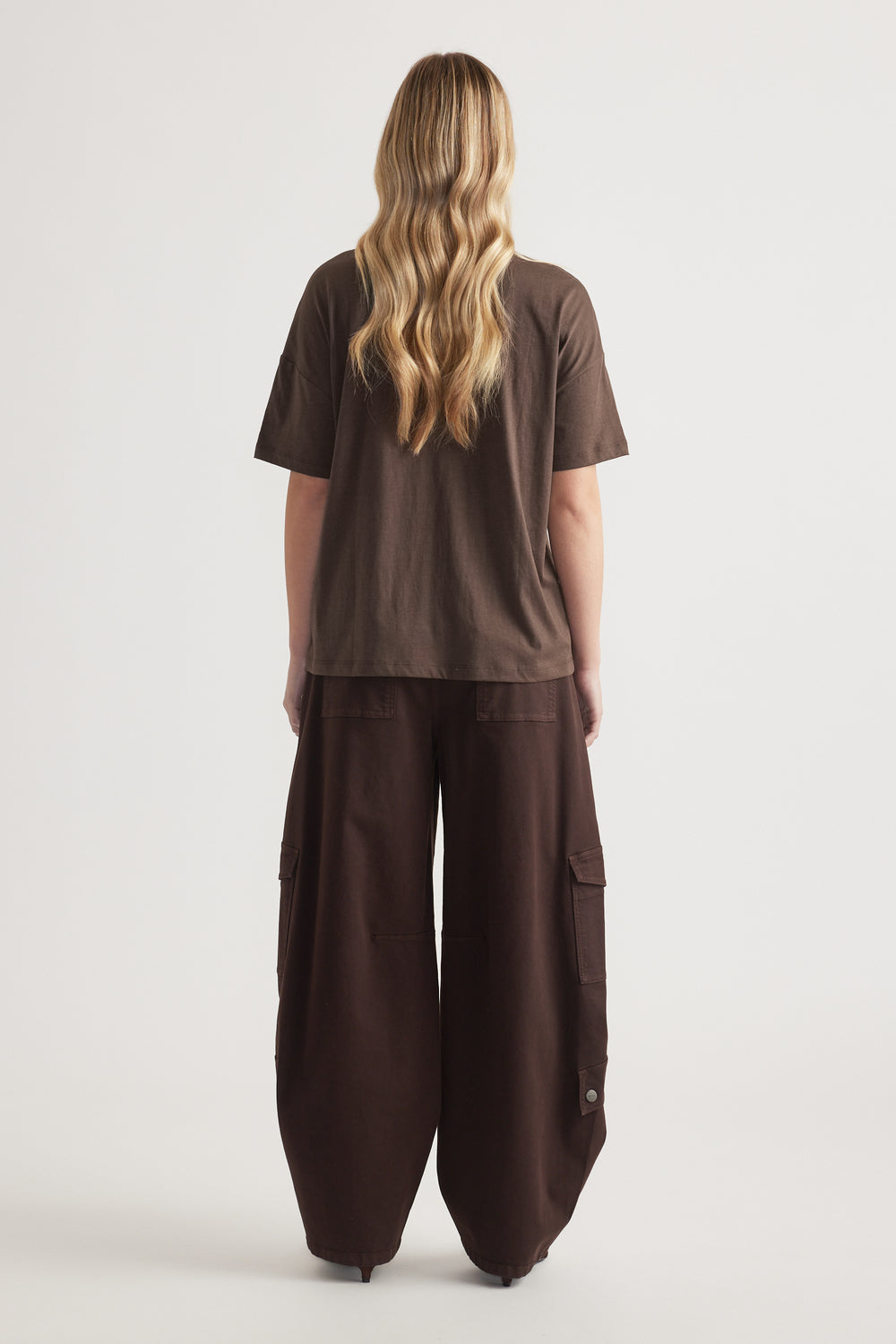 Back view of woman wearing a relaxed brown short sleeve tee with wide-leg cargo pants