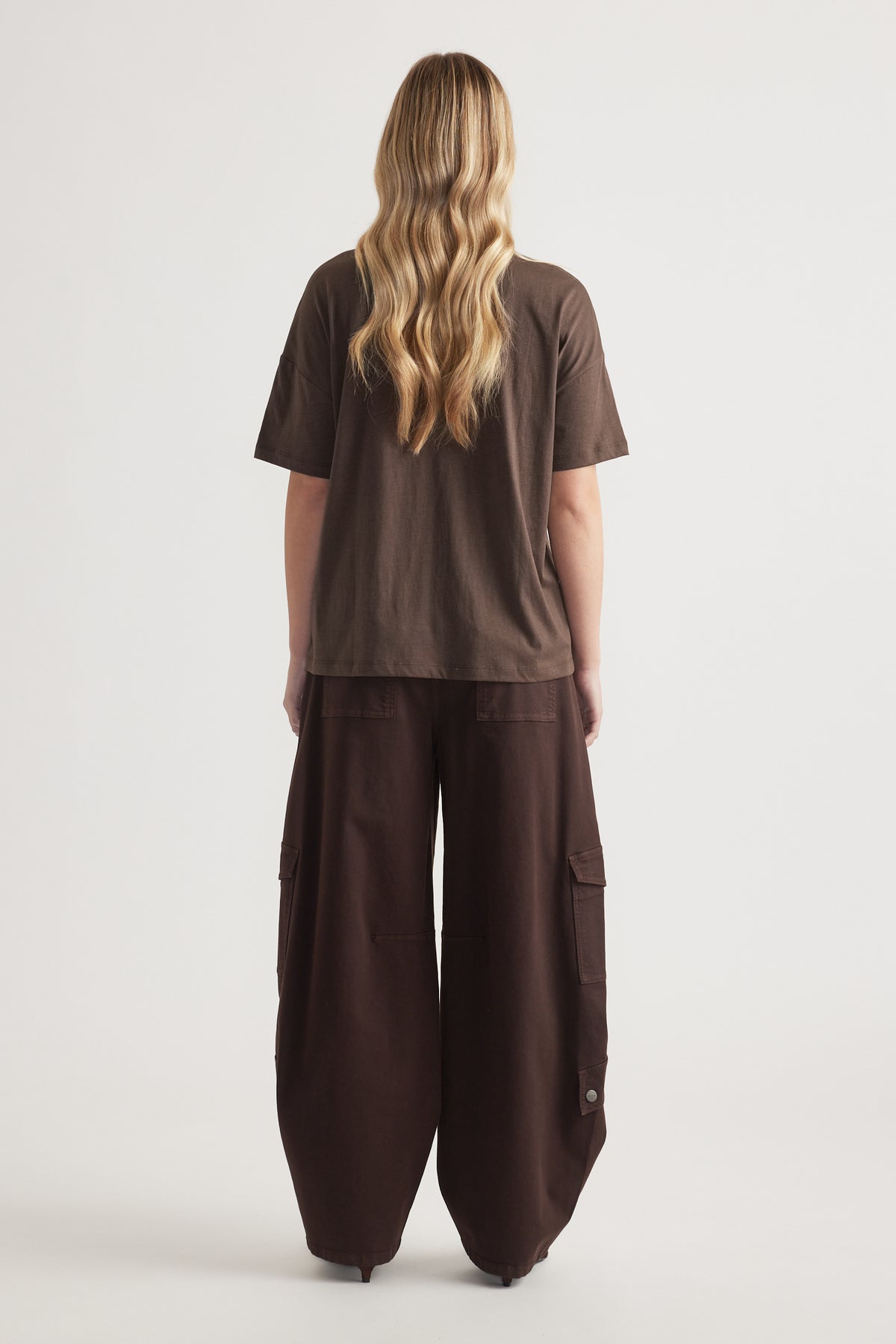 Back view of woman wearing a relaxed brown short sleeve tee with wide-leg cargo pants
